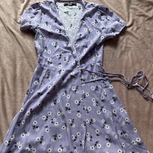 Blommig klänning - En lila klänning med blommor. Snörning runt midjan