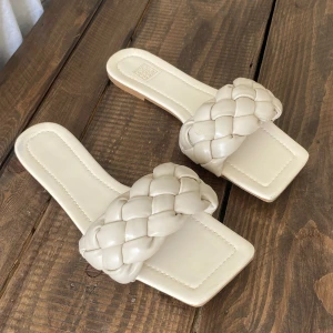 Tofflor - Flätade beige tofflor. I relativt fint skick. Liten skada längst fram, syns ej när man har på sig skorna. Storlek 37.