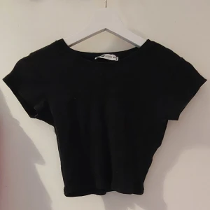 Svart croptop - Svart ribbad croptop, ganska tight, med korta ärmar. Använd ganska mycket, men forfarande i bra skick. 