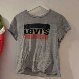 Ljus grå levis t-shirt - Ljus grå med levi's tryck på framsidan. Ganska liten med korta ärmar. Köpt secondhand, men bra skick. 
