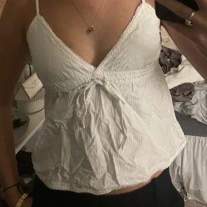 Vitt linne från Brandy Melville - Vit topp med knytning och justerbara band.