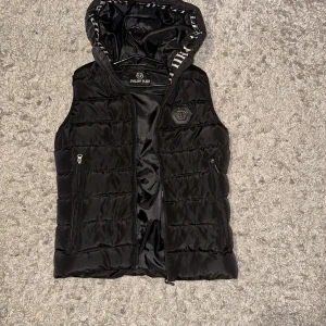 Väst - En ovanlig philipp-plein väst med fina detaljer, matchar med allt. Två fickor med dragkedja, en dragkedja som knäpper hela västen inga skador alls, blev tyvärr för liten. Bra skick oanvänd!