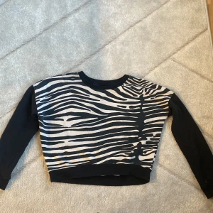 Tjocktröja - En beige och svart tjocktröja med svarta armar från Gina tricot  storlek xs