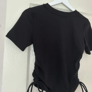 Svart t-shirt zara - Säljer denna snygga T-shirten med coola detaljer på sidan då den tyvärr blivit för liten. Är storlek m men skulle säga att det passar s också. Pris kan diskuteras💕💕