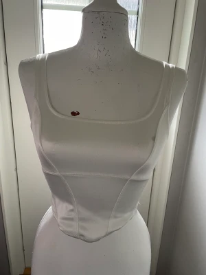 Vit topp - Korsett liknande topp i glansigt material. 