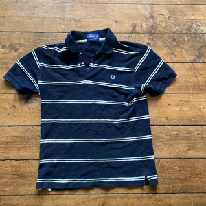 Fred perry pike - En vintage fred perry piké i seglarränder. Väldigt bra skick, inga fläckar eller skador.  Sitter mer som storlek M. Jag är runt 194 men då sitter den tajt och är lite för kort. Perfekt för någon runt 180.   Nypris: minst 1100, hittar ej denna på marknaden