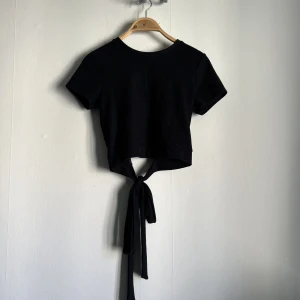 Topp med öppen rygg - En svart topp med öppen rygg och knytning bak. Säljer då den tyvärr inte kommer till användning 