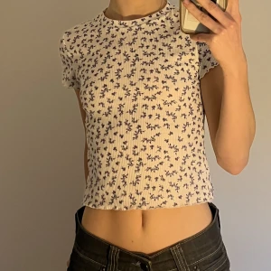 vit tröja med blåa blommor - vit tröja med blåa blommor från urbanoutfitters, strlk s. har några super ljusblåa fläckar som man inte lägger märke till eftersom blommorna oxå är ljusblåa men ändå defekt man bör veta om🤍