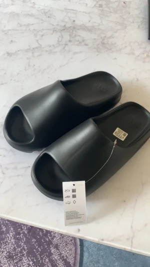 helt nya svarta yeezy slides - de är några storlekar för stora på mig det är därför jag säljer de och om man köper så får man med lådan