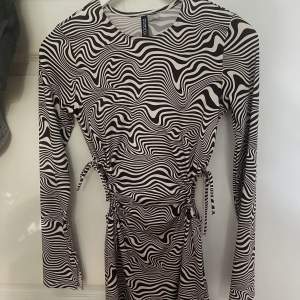 Mörkbrun och vit klänning från H&M med dragsko på båda sidor som man kan knyta hur man vill. Även en liten slit längst ut vid armen och på sidan. Storlek S. Aldrig använd. 40kr+frakt 🙌🏻