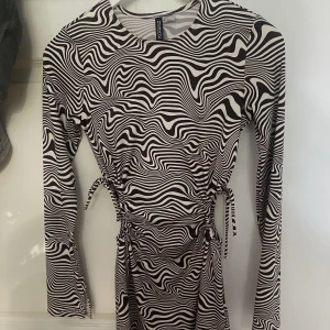 Dragsko klänning - Mörkbrun och vit klänning från H&M med dragsko på båda sidor som man kan knyta hur man vill. Även en liten slit längst ut vid armen och på sidan. Storlek S. Aldrig använd. 40kr+frakt 🙌🏻
