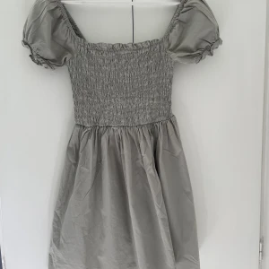 Sommarklänning  - En grå/grön klänning från ASOS. Superfin med puffärmar🌸 storleken är 32 men passar mig som har S i vanliga fall. Nypris 450 kr.