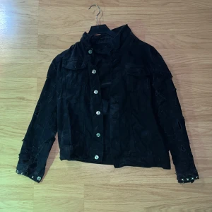 Svart denim jacka  - En svart denim jacka jag har slitit ut armarna med vilje så den ska se mer ruff ut och satt fast nitar längst ner på dens sleevs 