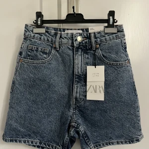 Zara bermuda jeansshorts - Fina oanvända Zara bermuda shorts, mom fit. Hög midja och mycket bekväm. I en tvättad blå jeansfärg. Storleken är 34 EUR, 2 USA. Taggen är fortfarande fäst, så villkoren är perfekta. Klicka gärna på köp nu!💙 