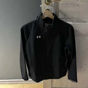 Under armor  - Svart vind jacka av märket under armor. Jackan är i storlek L för barn. 