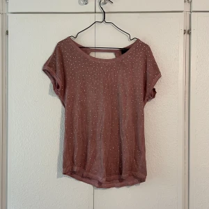 T-shirt  - Fin T-shirt med stenar som glittrar på framsidan och hål i ryggen på baksidan. 