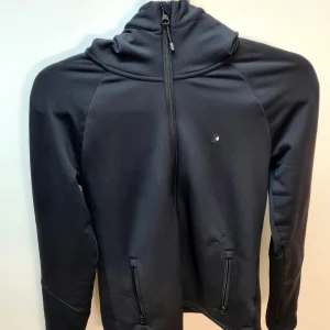 Peak Performance Rider Zip W - Har ett litet hål på vänster sida vid fickan som jag har sytt ihop. Påverkar inte funktionen, därav priset. För övrigt i bra skick. - Mellanlagerjacka för dam - Mjukt material med 4-vägsstretch  - Fukttransporterande och snabbtorkande - Med huva