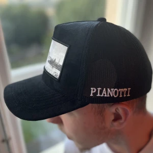 PIANOTTI KEPS - Pianotti keps i nyskick, aldrig använd. Tryck av Stockholm i sammet material. De bruna som syns bakom nätet är kartong för att hålla den i form. 