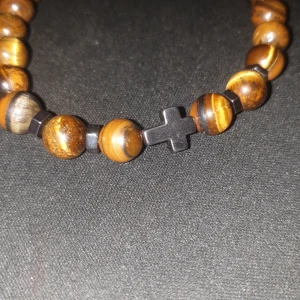 Pärlarmband kors orangebrun - Köpte det här armbandet men det var för stort så nu säljer jag det. Ord Pris: 140kr.