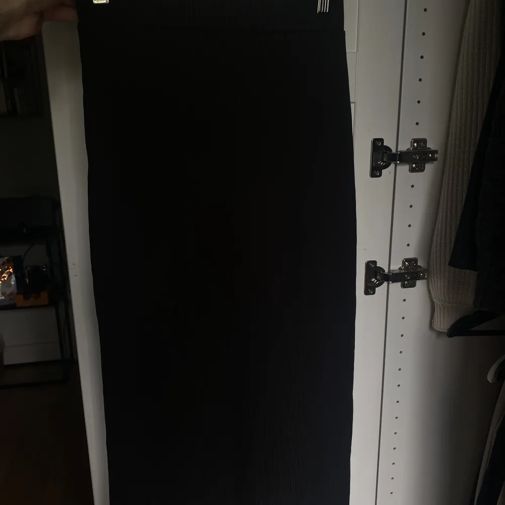 Lång ribbad svart maxi kjol med en slita på en sidan. Har en tajt passform trotts slitsen, jättefin på men är för liten för mig. Kjolar.