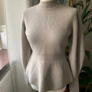 Stickad tröja H&M ull figursydd - Figursydd tröja med peplum i ull från H&M. Grå/ beige. Säljer pga passade inte mig.