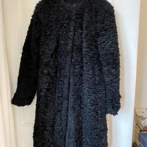 Svart fuskpälskappa - Svart kappa i fuskpäls från HM med rund halsringning. Välanvänd men i fint skick. Köparen betalar frakten.