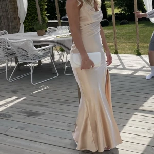 Balklänning  - Säljer min fina balklänning. Champagne färgad med öppen rygg och knytning samt slits. Använd en gång så den är i bra skick. 