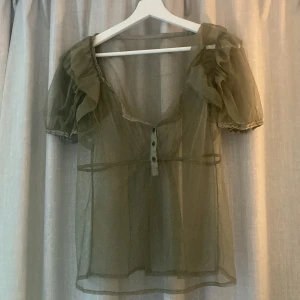 Mesh topp med puffärmar  - Matchande (till kjolen) grön, meshtopp. Gulddetaljer vid sömmar. 