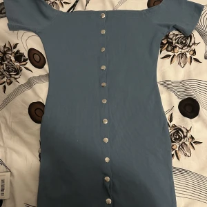 Blå off shoulder klänning  - Helt oanvänd off shoulder klänning med knappar 