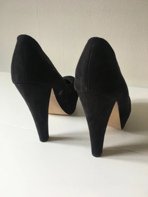 Svarta klackskor - Svarta klackskor i mockaimitation.  Använda någon enstaka gång.  Litet skav på insidan av skon (se sista bilden) men syns endast för den skarpögda. 