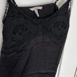 Skitsnyggt svart linne från H&M med spets detalj på framsidan, i storlek Xs. Säljer för att de är lite för litet. Linnet är oanvänt men testat en gång💕