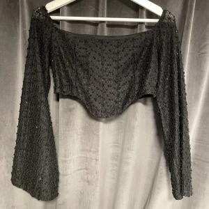Glittrig croppad topp 🖤 -  Svart/glittrig långärmad topp med textur från NAKD, supersnygg men säljer pågrund av att den är lite för kort för mig.