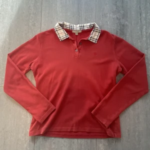 Burberry London rugbytröja - Säljer en trendig och snygg burberry rugbytröja!! Den är Storlek L men skulle säga att den passar dig som är runt 170cm. Nypris runt 5000kr tror jag. Mitt pris endast 499kr!! Kontakta vid minsta intresse! 🫡