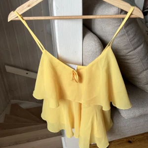 gul topp med volanger  - storlek uppskattad xxx-xs! bysten (under armhålorna) 83cm. 