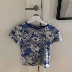 Blommig t-shirt - Hej! Nu säljer jag denna super fina blommiga blåa t-shortsen för att ajg inte får någon alls användning utav den. Den är min mammas gamla så därför vet jag inte hur använd den är tyvärr men den har inga defekter eller så❤️kontakta för mer bilder och info❤️💓