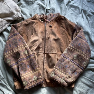 Hooded läderjacka - Fet skön å varm jacka med huva. Äkta mocha läder och bomull som material. Feta mönster på tyget. Size M men passar Mer som S Skick: 9/10