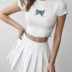 Set av en vit croppad t-shirt med en blå fjäril på och blå söm samt en vit tennis kjol. Från Shein. Storlek M men liten i storleken.