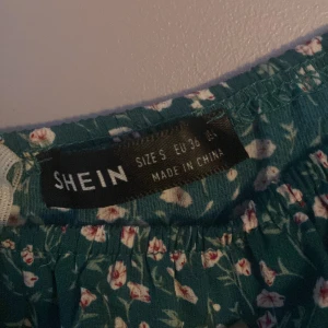Blommig klänning  - Jätte fin grön blommig klänning från Shein. Sitter jätte fint tight i midjan och lite halvt utsvänt nertill.