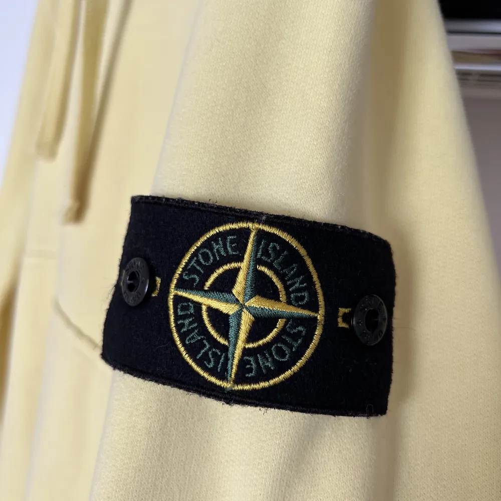 Pastellgul hoodie från Stone Island. Skick: 9/10 Storlek: M Endast använd ett fåtal gånger.. Hoodies.