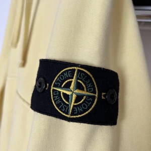 Stone Island Hoodie - Pastellgul hoodie från Stone Island. Skick: 9/10 Storlek: M Endast använd ett fåtal gånger.