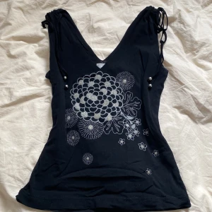 Svart topp - Svart topp med dubbelt tyg och glittrigt tryck. V-ringad och ganska tight