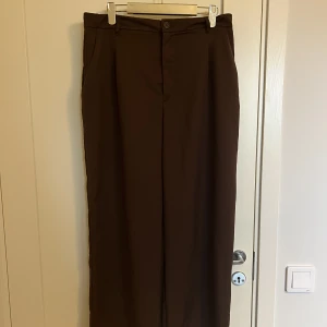 Kostymbyxor  - Superfina bruna kostymbyxor från HM!! Storlek 46 och i väldigt bra skick! De har en knapp på utsidan, dragkedja och stretch i midjan Innerbenslängd: ca 75cm, Midjemått: ca 43,5cm till 50,5cm 