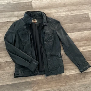Skinnjacka (PU) - Supersnygg ”skinn”-jacka (PU) från Oboy i storlek 36. Slitningar på insidan av kragen samt i nacke och på axel finns, se bild 2 och 3.