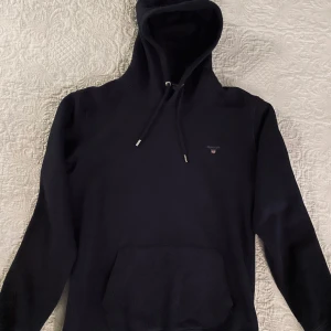 Hoodie Gant, stlk M/L - Svart mjuk hoodie från Gant. Storlek L men i mindre version så funkar bra som M+ också.  Använd en gång så nyskick. Pris i butik: 1200 SEK. Obs: tredje fotot är taget från Gants hemsida för ge en bild av hur den ser ut på.