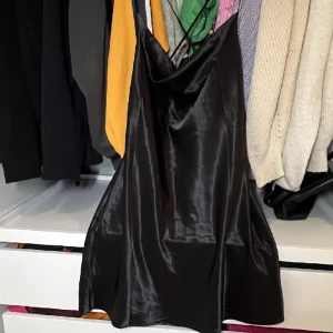 Svart satin klänning - En fin svart satin klänning. Ganska kort men jättefin. En öppen rygg och ganska urringad