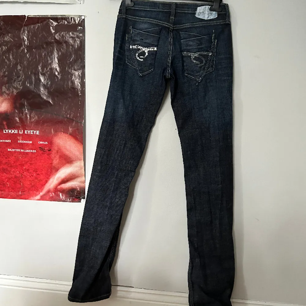 Vintage jeans! Svincoola med 2 nitar och knäppning med knappar. Bakfickor med glitterpaljetter. Långa, passar 180+. Storlek w27 L34. I vanlig storlek mellan XS-S. Jeans & Byxor.