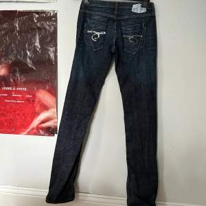 Vintage jeans! Svincoola med 2 nitar och knäppning med knappar. Bakfickor med glitterpaljetter. Långa, passar 180+. Storlek w27 L34. I vanlig storlek mellan XS-S