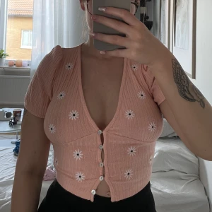 Söt sommartopp - Söt sommartopp med blomdetaljer på. Säljer då den tyvärr inte kommer till användning. Är i bra skick. Storlek S.