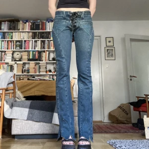Lågmidjade 200-tals utsvängda jeans - Ascoola lågmidjade jeans med snörning framme och blad detaljer längst ner. Jag är 178 och de är perfekt långt för mig. Midja tvärs över: 37 med snörningen som tajtast Innerbenslängd: 86 cm Jag har storlek 36 och de passar bra på mig.