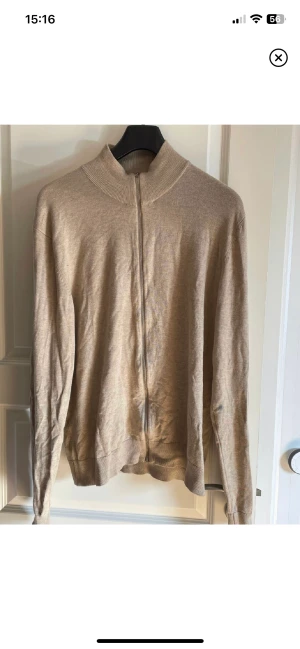 beige stickad lindberg fullzip swetshirt herr stl XL - säljer denna otroligt fina zip hoodien i storlek XL, denna passar även för stl L riktigt bra. märket lindberg, köptes för 599kr. hör av er vid frågor. pris går att diskutera